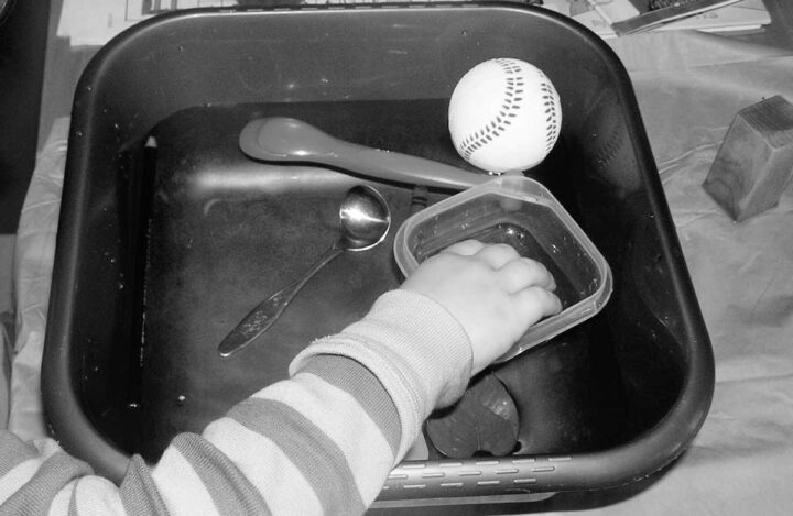 Float or sink experiment with child adding items to water bucket