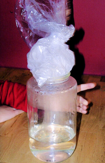 Water in glass jar topped by bag of ice