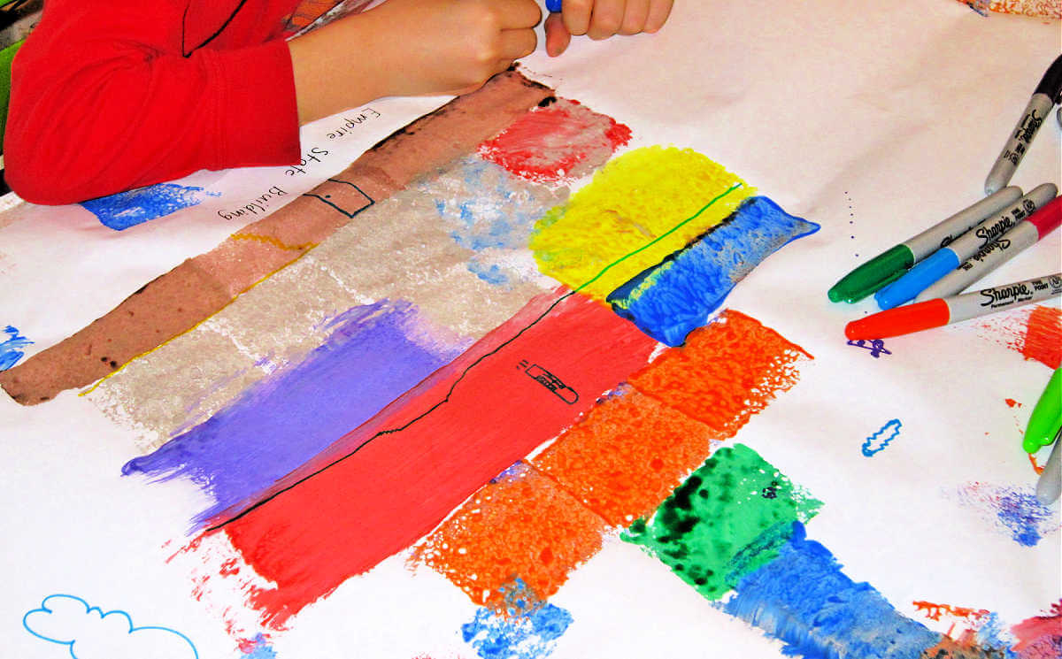 Child drawing on sponge painted paper.