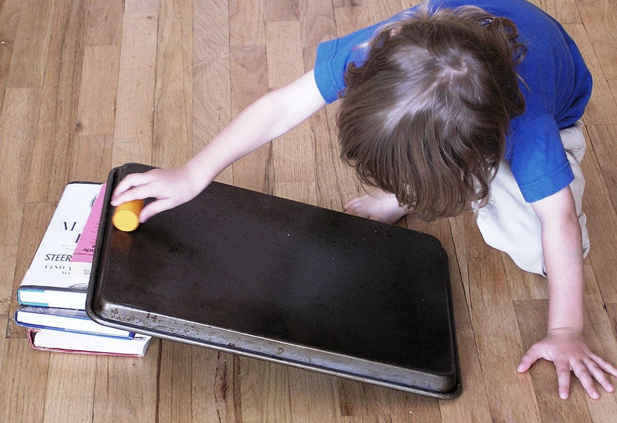 Child rolling block down homemade ramp