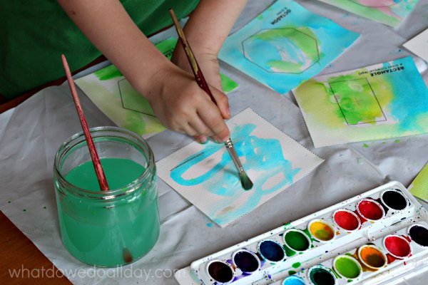 Child using watercolors to design a shapes book for a math art project. 